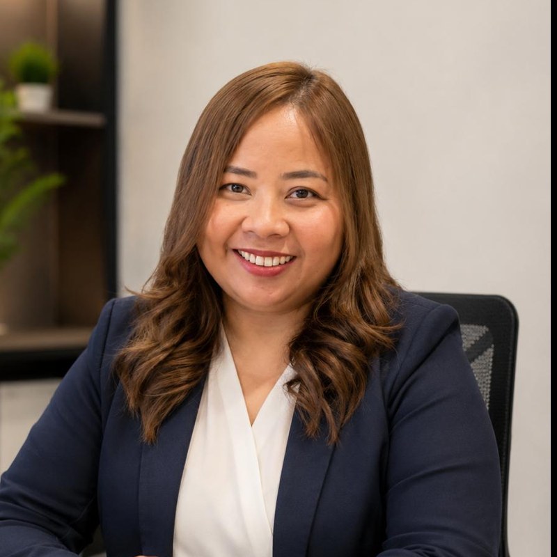 Richelle Refugia, Operations Director of Stressfree Business Support, smiling at her desk in a navy blazer